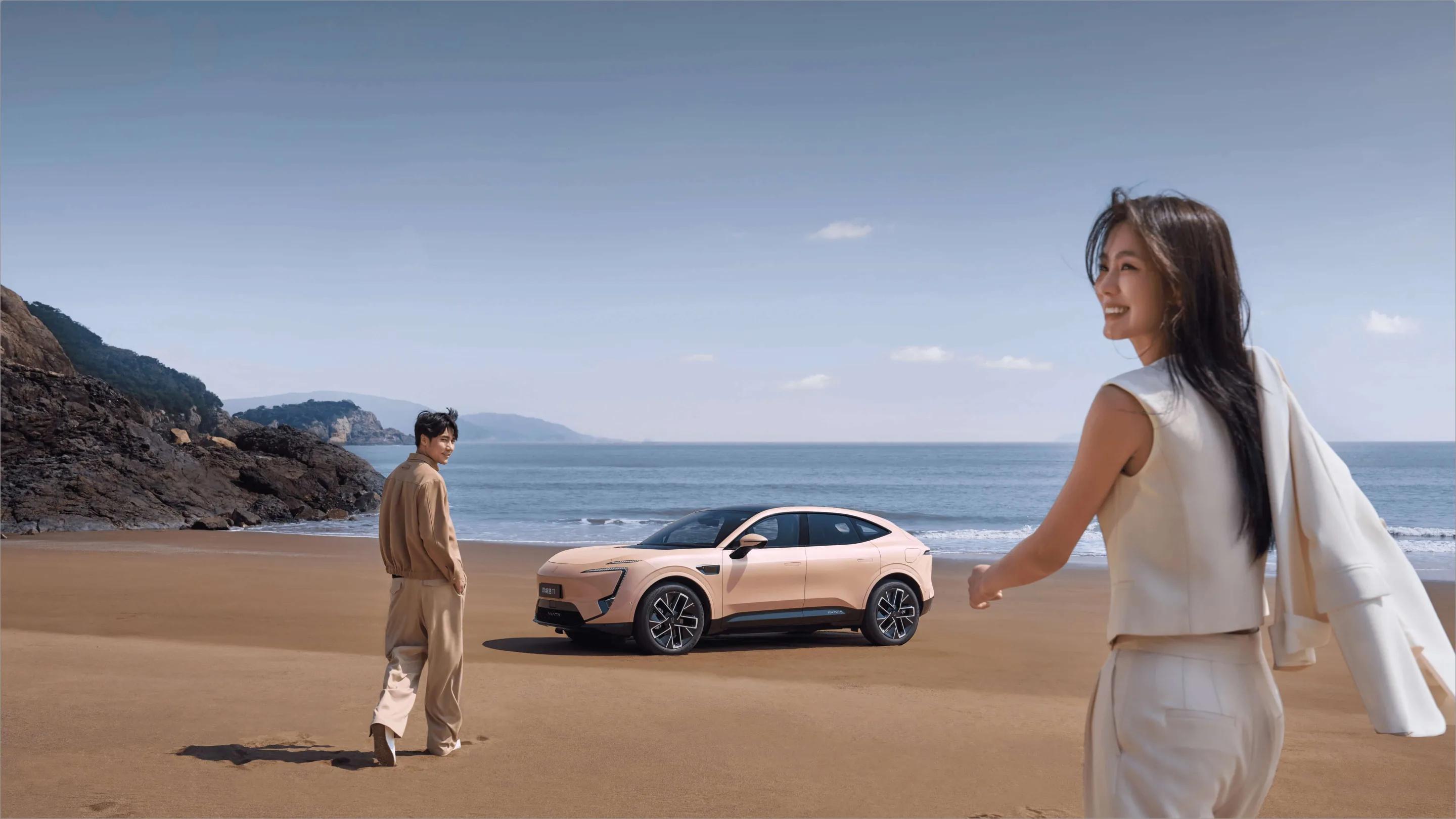 Una pareja camina por la playa hacia el mar; detrás, un AVATR 11 estacionado sobre la arena